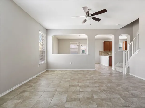 an empty room with chandelier fan and windows