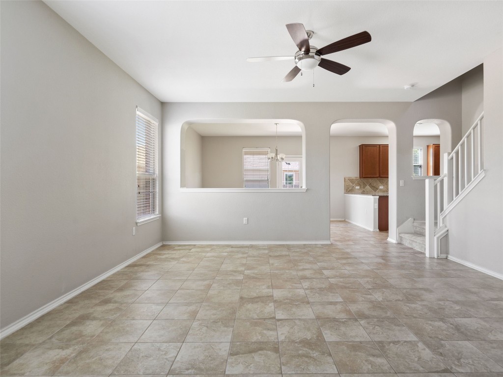 7633 Rio Pass Austin, TX 78724 - Photo 3 of 23 Unfurnished room featuring a ceiling fan, healthy amount of natural light, hanging lights, and arched walkways
