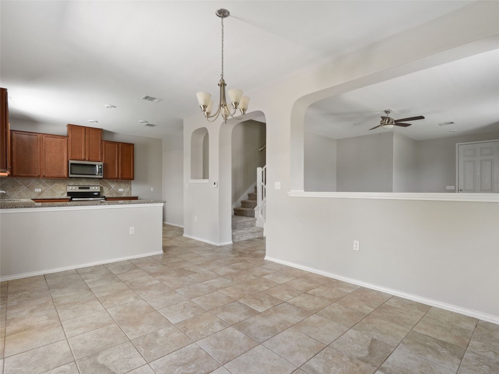 7633 Rio Pass Austin, TX 78724 - Photo 23 of 23 Kitchen with suspended lighting, arched walkways, stainless steel appliances, wood finish cabinets, and open floor plan