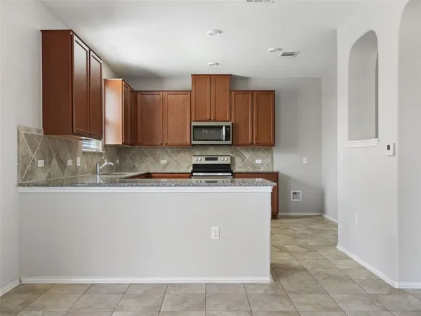 a kitchen with granite countertop a refrigerator and a stove top oven