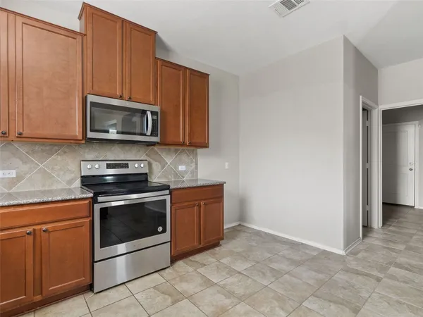 a kitchen with granite countertop a stove microwave and cabinets