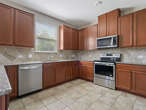 a kitchen with granite countertop a stove top oven microwave and cabinets