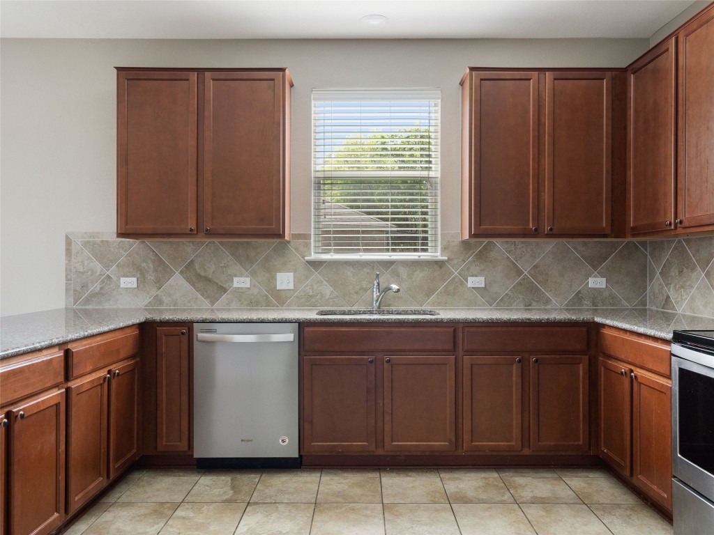 7633 Rio Pass Austin, TX 78724 - Photo 8 of 23 Kitchen with light stone countertops, stainless steel appliances, and light tile patterned flooring