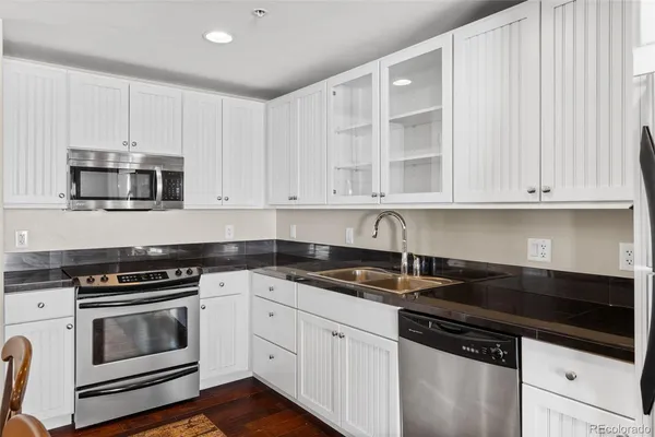 a kitchen with granite countertop white cabinets and stainless steel appliances