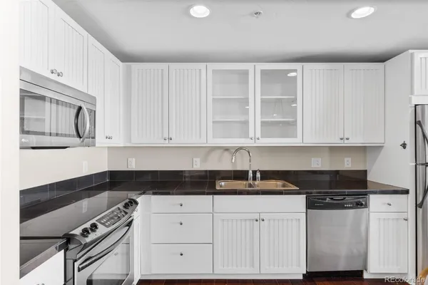 a kitchen with granite countertop white cabinets and black appliances
