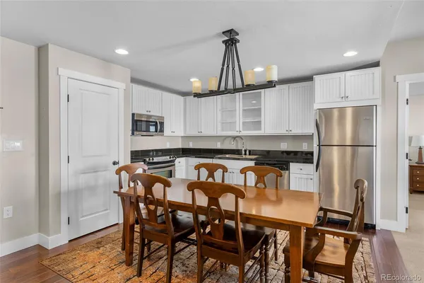 a kitchen with stainless steel appliances a refrigerator a stove a dining table and chairs