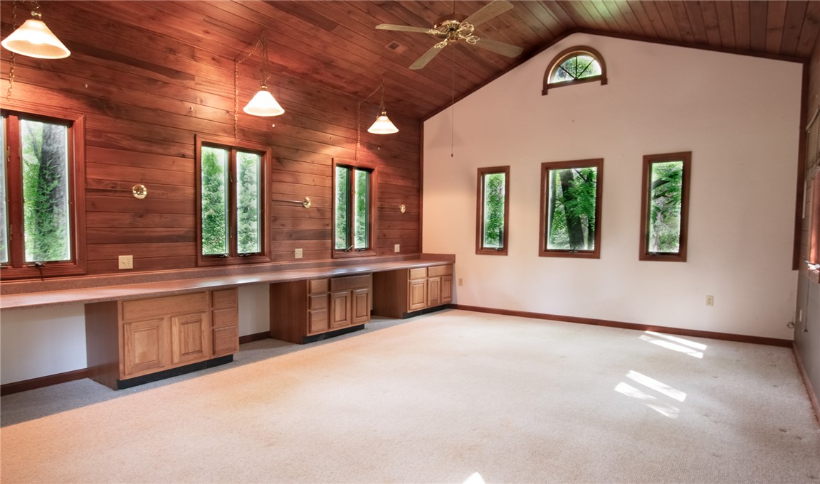 200 Chenault Road Townville, SC 29689 - Photo 26 of 47 A spacious room features a rich wood-paneled accent wall with built-in cabinetry, illuminated by natural light and pendant fixtures.