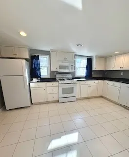a kitchen with white cabinets and refrigerator