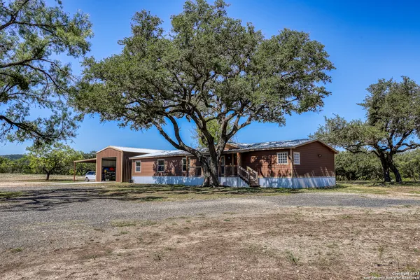 a front view of a house with large trees