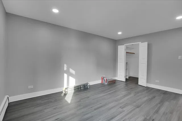 a view of an empty room with wooden floor and closet