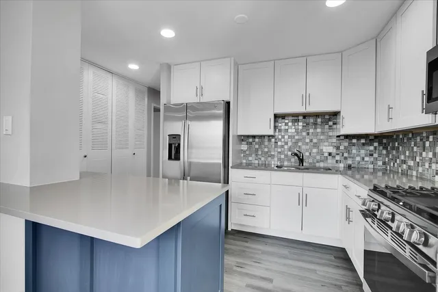a kitchen with stainless steel appliances a sink a stove and cabinets