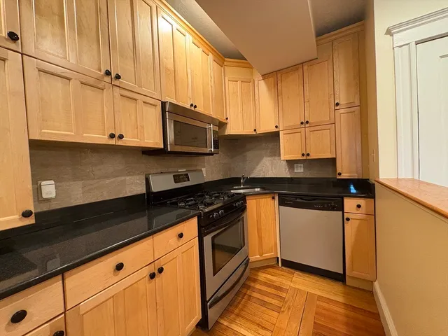a kitchen with stainless steel appliances granite countertop a sink a stove and cabinets