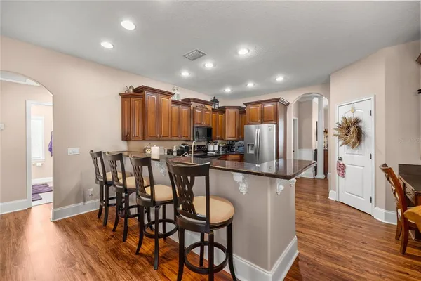 a kitchen with stainless steel appliances kitchen island granite countertop a table chairs and a refrigerator