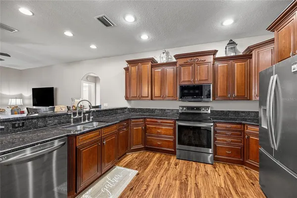 a kitchen with stainless steel appliances granite countertop a stove refrigerator sink and microwave