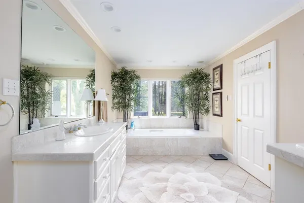 a spacious bathroom with a tub sink and mirror