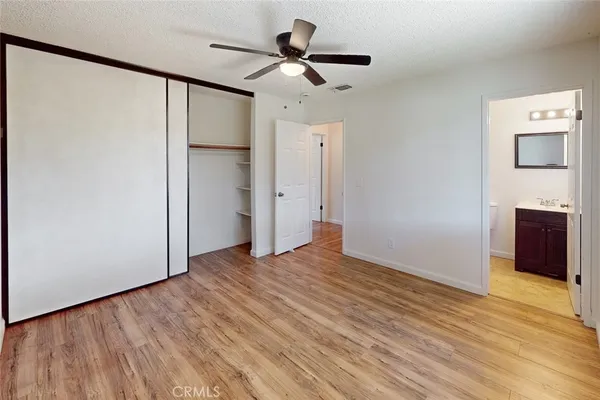 a view of an empty room with wooden floor and a ceiling fan