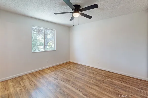 an empty room with wooden floor ceiling fan and windows