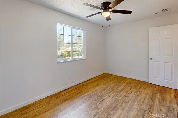 a view of empty room with wooden floor and fan