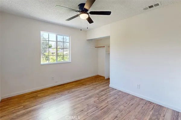 a view of empty room with wooden floor and fan