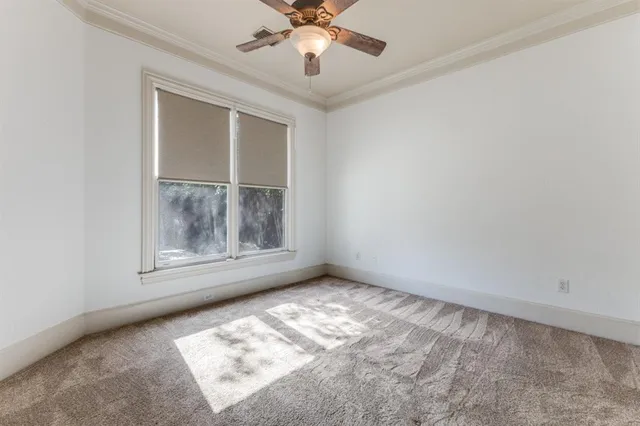an empty room with a chandelier fan and windows