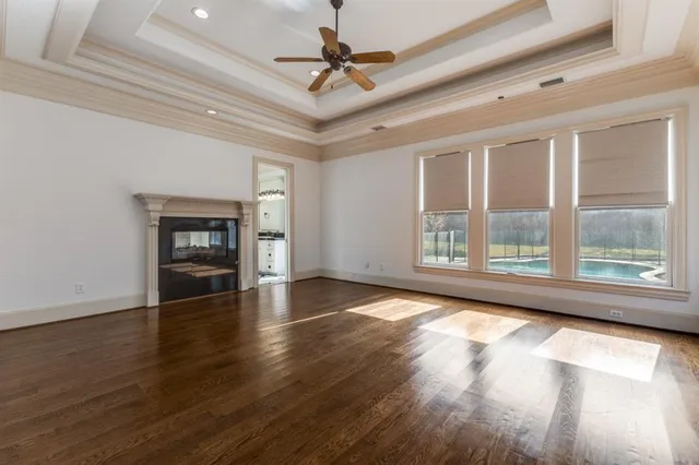 a view of an empty room with window and wooden floor