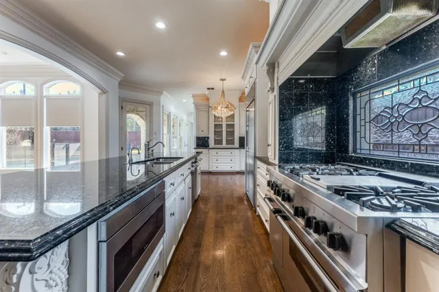 a large kitchen with stainless steel appliances granite countertop a stove and a large window