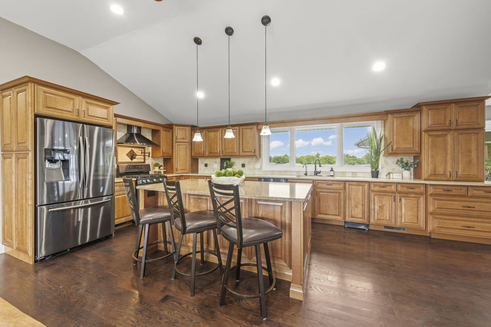 10N862 Muirhead Road Elgin, IL 60124 - Photo 15 of 47 a kitchen with stainless steel appliances kitchen island granite countertop a refrigerator a stove a dining table and chairs with wooden floor
