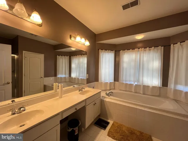 a bathroom with a tub a sink and a large mirror