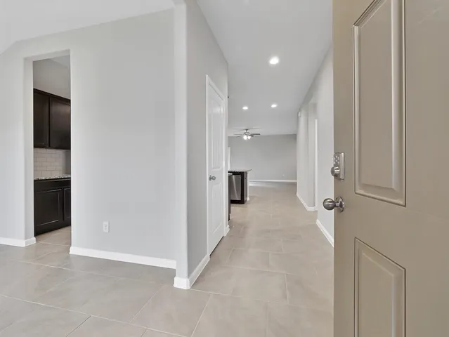 an empty room with chandelier fan and windows
