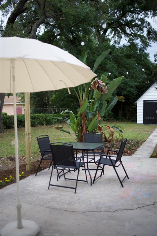 1126 Ruby Street Lakeland, FL 33815 - Photo 35 of 38 a view of a patio with table and chairs under an umbrella with a small yard and potted plants