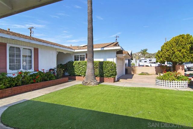 a view of a house with a big yard potted plants and large tree