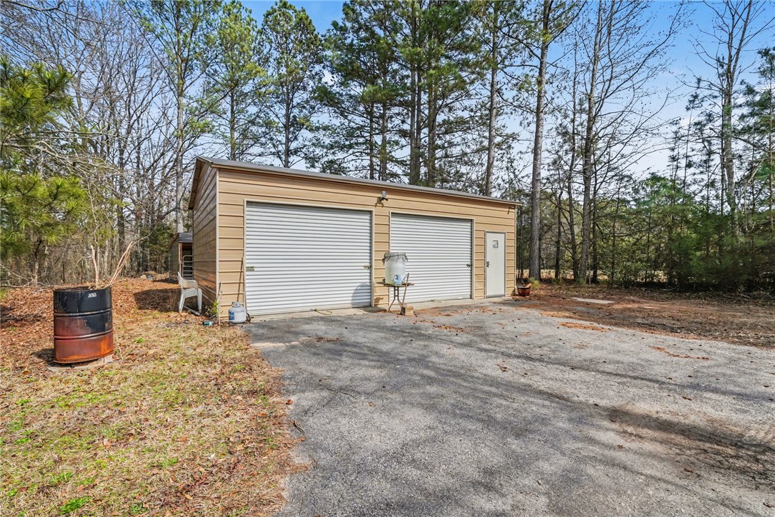 1004 Chapman Road Honea Path, SC 29654 - Photo 29 of 30 This practical garage structure offers ample space for vehicles and storage amidst a natural wooded setting.