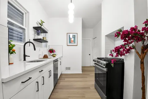 a kitchen with white cabinets and wooden floor