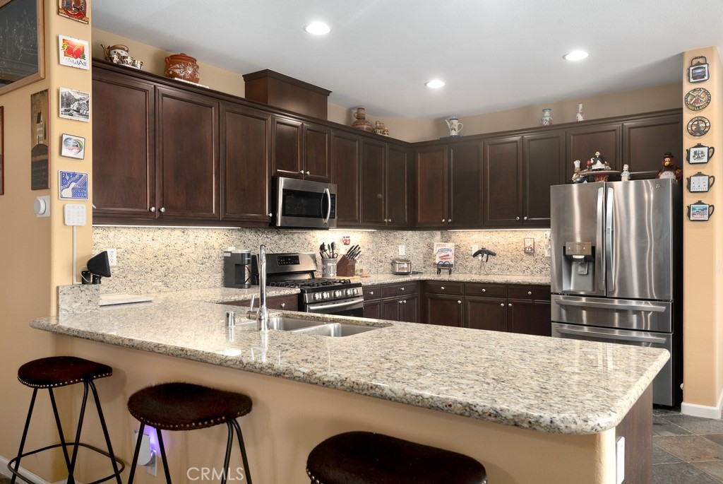 130 Daylily Drive Perris, CA 92571 - Photo 14 of 43 a kitchen with stainless steel appliances granite countertop a sink refrigerator and cabinets