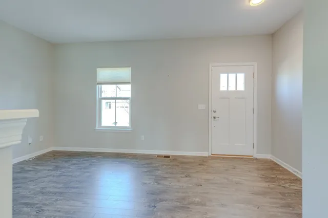 an empty room with wooden floor and windows