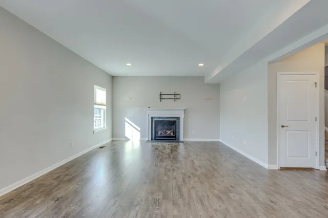 an empty room with wooden floor fireplace and windows