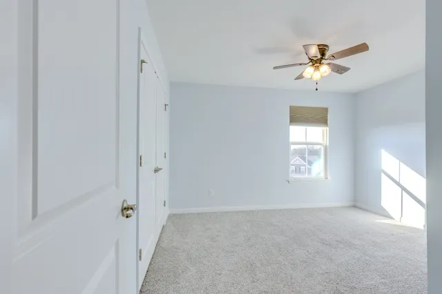 an empty room with a ceiling fan and window