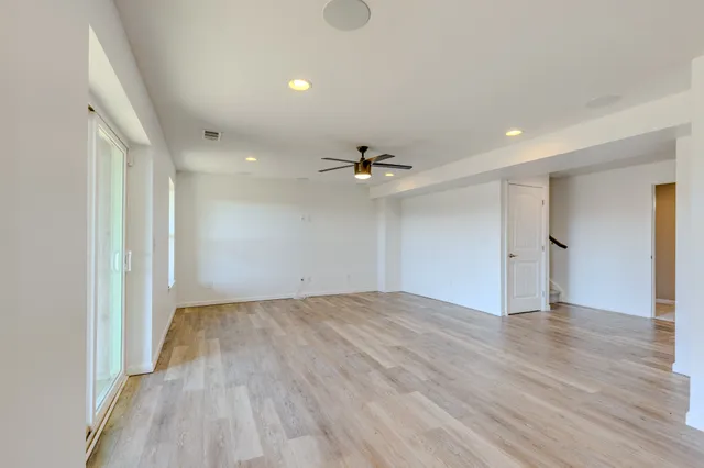 a view of an empty room with window and wooden floor