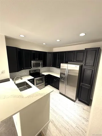 a living room with stainless steel appliances furniture and kitchen view