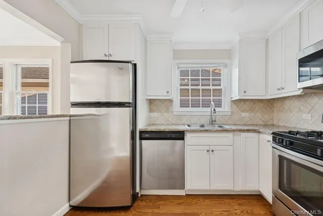 a kitchen with granite countertop a sink cabinets stainless steel appliances and a window
