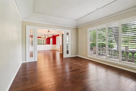 a view of a livingroom with wooden floor a ceiling fan and windows