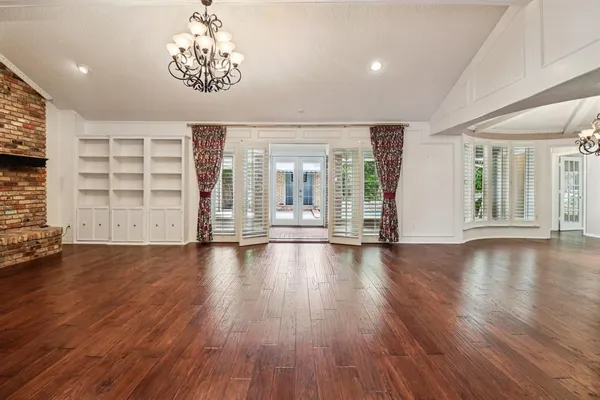 an empty room with wooden floor fireplace and windows