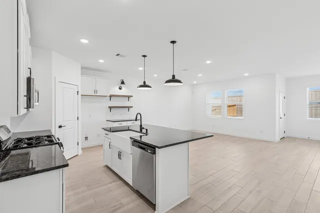 a kitchen with stainless steel appliances granite countertop a sink stove and refrigerator