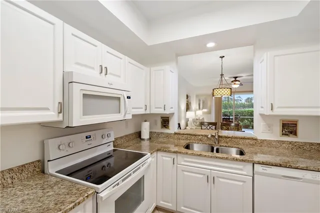 a kitchen with granite countertop white cabinets sink and stainless steel appliances