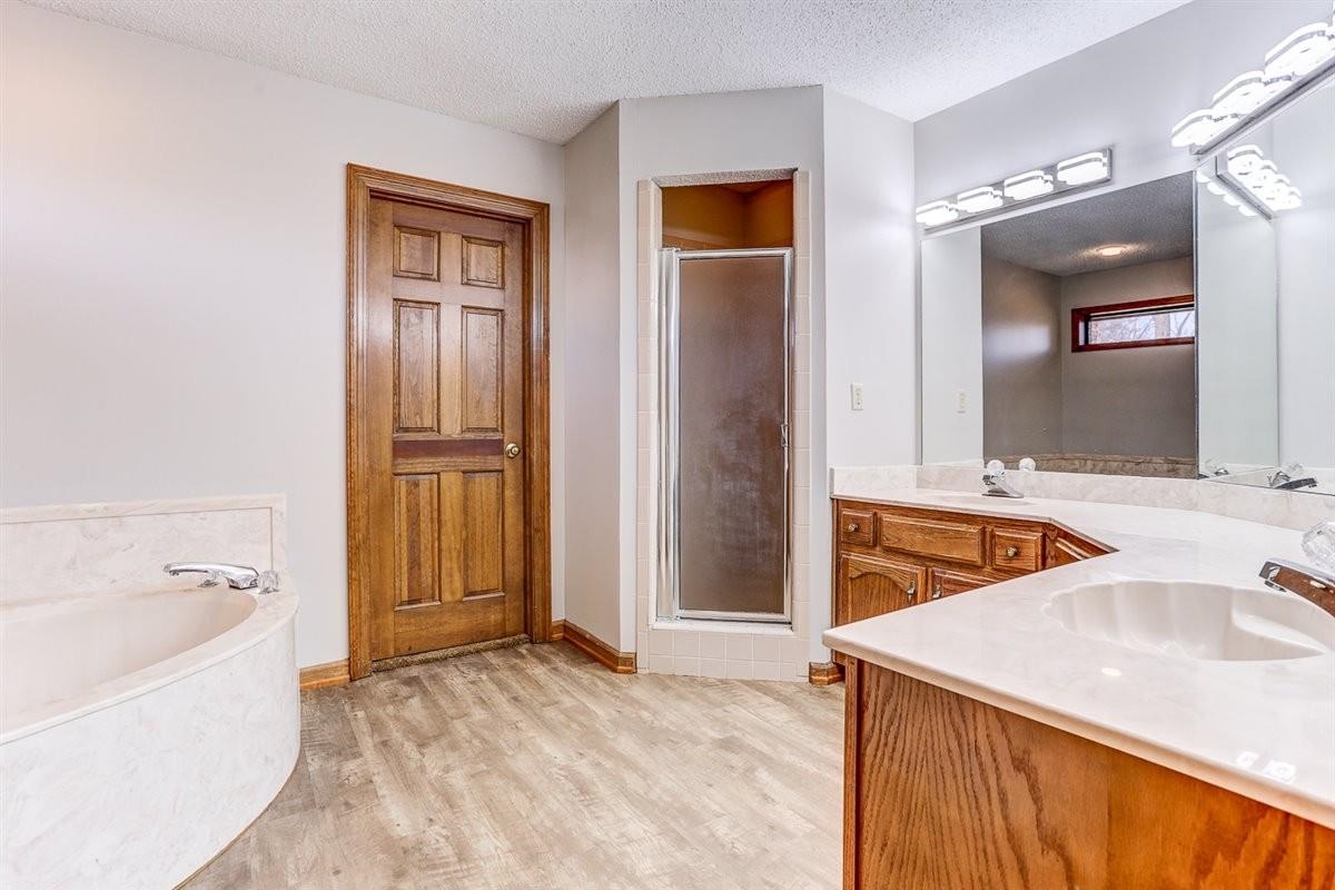 3915 Oak Road Bartlett, TN 38135 - Photo 8 of 28 Bathroom with a textured ceiling, a bath, light wood finished floors, a shower stall, and double vanity