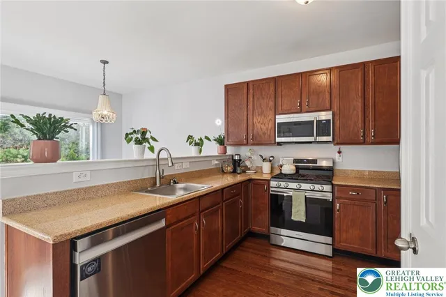 a kitchen with granite countertop wooden cabinets stainless steel appliances and a sink