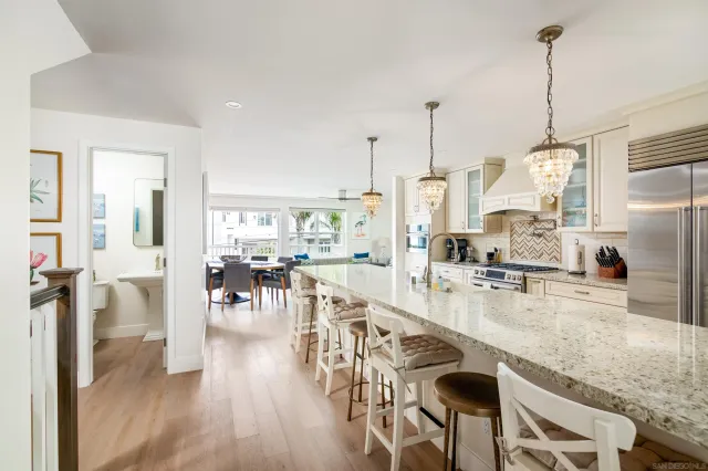 a kitchen with stainless steel appliances granite countertop a stove top oven a sink a dining table and chairs with wooden floor