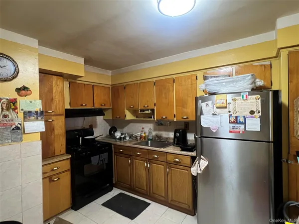 a kitchen with stainless steel appliances a refrigerator a sink and wooden cabinets