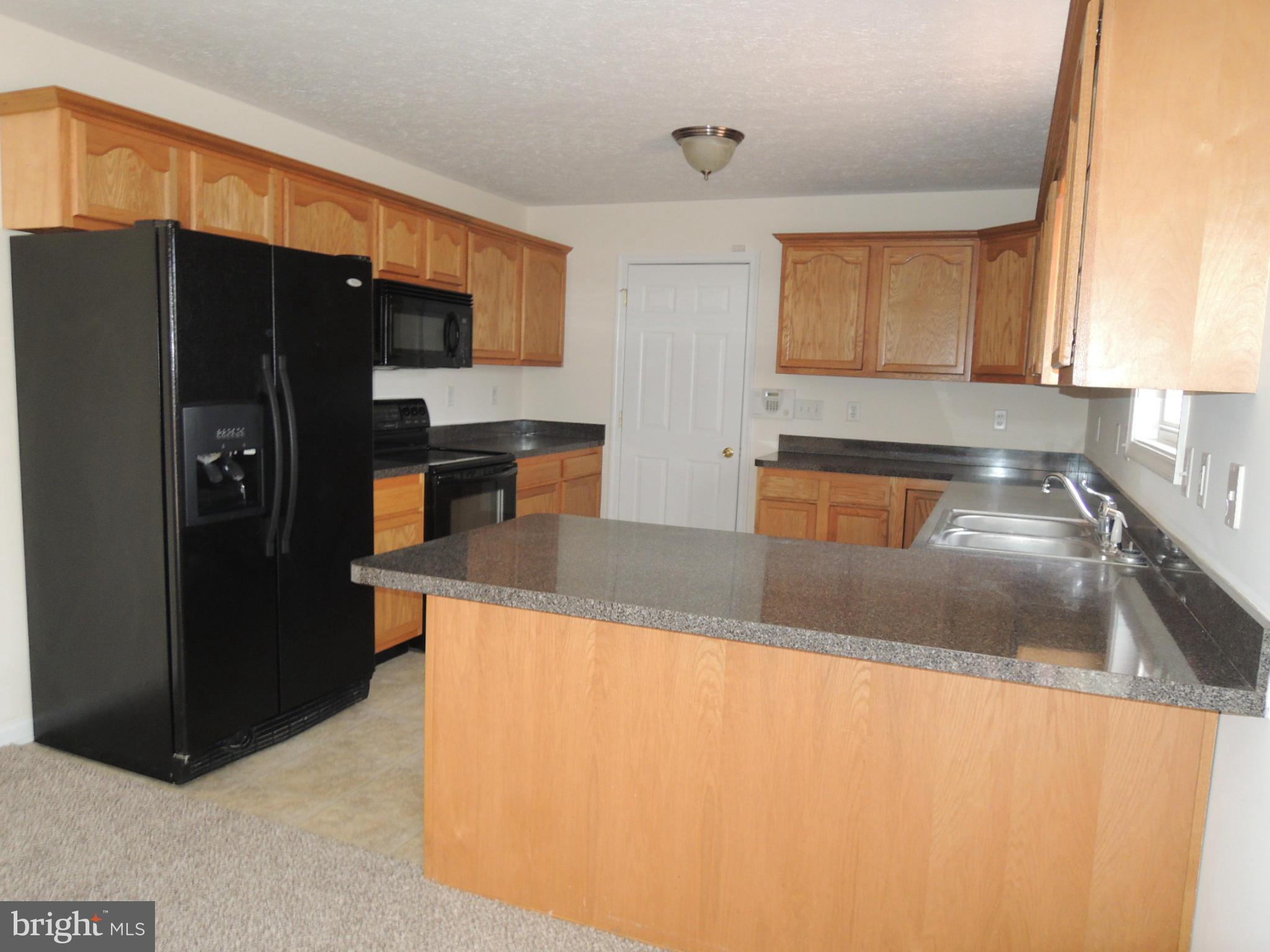 39 Raft Court Inwood, WV 25428 - Photo 10 of 30 a kitchen with granite countertop a refrigerator and a sink