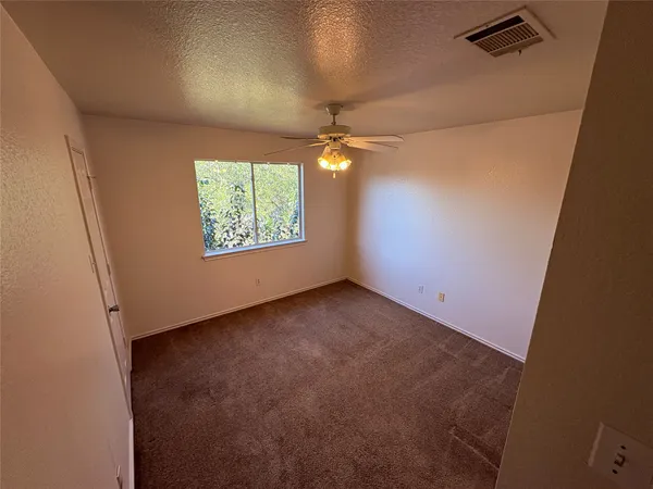 an empty room with windows and a ceiling fan